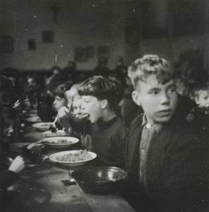 876782 Afbeelding van een grote groep kinderen die aan het eten is in een klaslokaal van de Piusschool (Oudegracht 33) ...